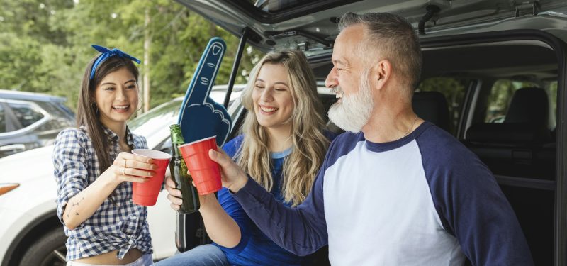 friends-sitting-and-drinking-in-the-car-boot-at-a-tailgate-party.jpg