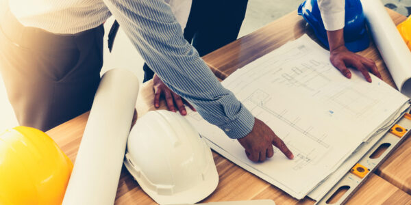 Team of engineers discussing architecture plan sketch at the construction site. Vintage tone